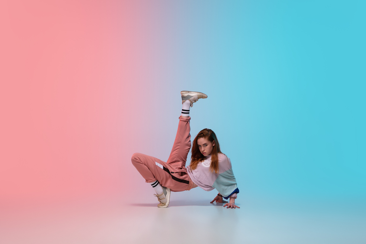 Girl Dancing Hip-Hop in Stylish Clothes on Gradient Background at Dance Hall in Neon Light.